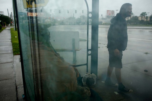 TAMPA, FL - SEPTEMBER 10: With the sky darkening and the wind picking up, two men hide from the rain at a bus stop as they debate flagging down a police officer to ask for a ride to a shelter ahead of Hurricane Irma on September 10, 2017 in Tampa, Florida. Hurricane Irma made landfall in the Florida Keys as a Category 4 storm on Sunday, lashing the state with 130 mph winds as it moves up the coast.   Brian Blanco/Getty Images/AFP