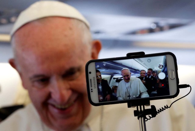 A journalist uses a mobile phone as Pope Francis speaks with media while on board his plane bound to Bogota, Colombia, September 6, 2017. REUTERS/Stefano Rellandini