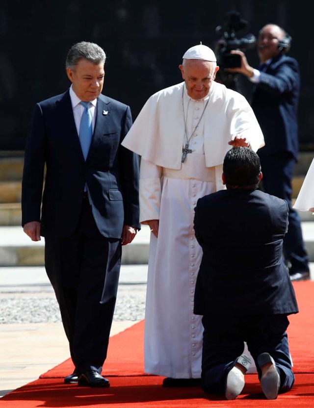 A faithful kneels as Colombia's President Juan Manuel Santos (L) and Pope Francis arrive at Narino presidential palace in Bogota, Colombia September 7, 2017. REUTERS/Stefano Rellandini