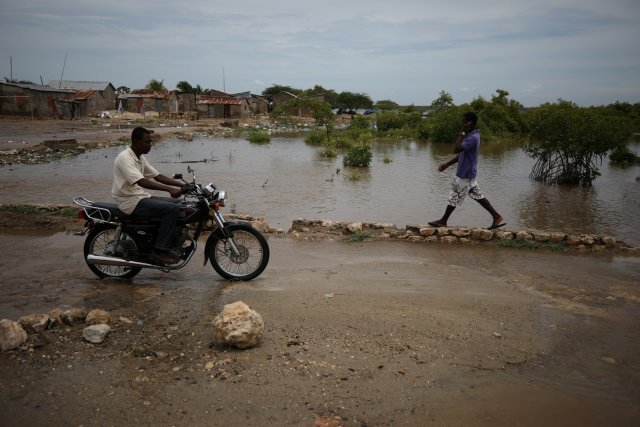 Personas pasan al lado de una inundación ocasionada por el huracán Irma en Haití. REUTERS/Andres Martinez Casares