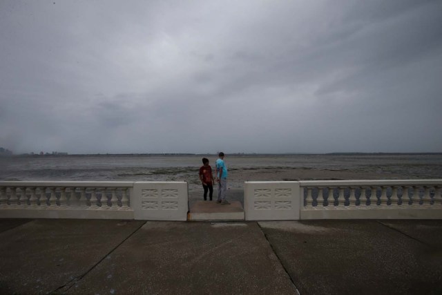 Boys look out at Hillsborough Bay after water receded from the harbour ahead of the arrival of Hurricane Irma in Tampa, Florida, U.S., September 10, 2017. REUTERS/Chris Wattie