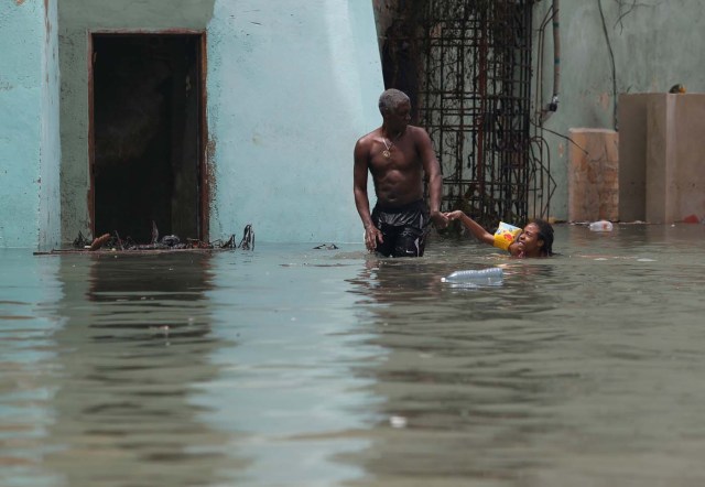 A man helps a girl with a swim float as she plays in a flooded street, after the passing of Hurricane Irma, in Havana, Cuba September 10, 2017. REUTERS/Stringer NO SALES. NO ARCHIVES