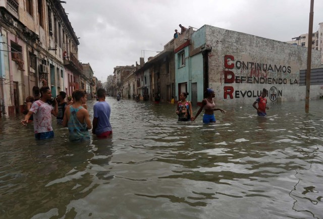 People wade through a flooded street, after the passing of Hurricane Irma, in Havana, Cuba September 10, 2017. The sign on the wall reads "We will continue to defend the revolution." REUTERS/Stringer NO SALES. NO ARCHIVES