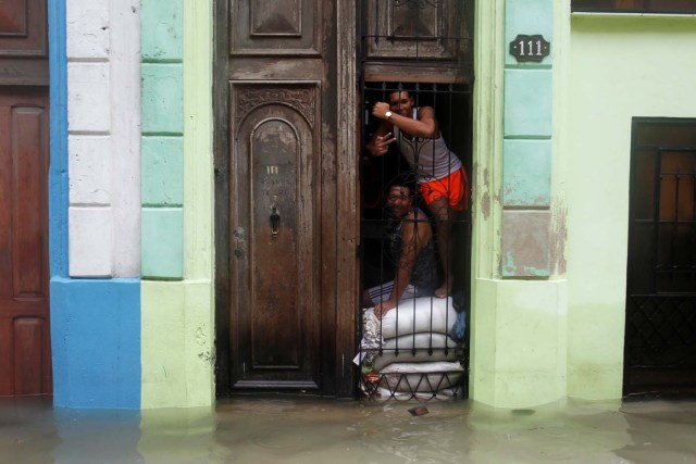 People pose for a photograph as sandbags are placed in the entrance of a home, after the passing of Hurricane Irma, in Havana, Cuba September 10, 2017. REUTERS/Stringer NO SALES. NO ARCHIVES