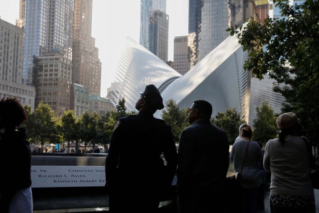 People pause at the edge of the South reflecting pool at the National September 11 Memorial and Museum during ceremonies marking the 16th anniversary of the September 11, 2001 attacks in New York, U.S. September 11, 2017. REUTERS/Brendan McDermid