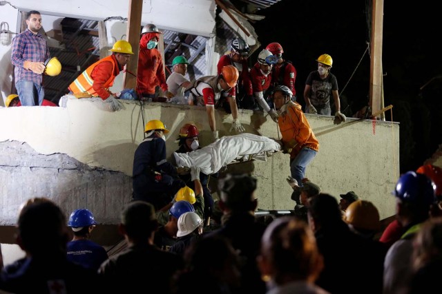 Rescue workers remove a dead body after searching through rubble in a floodlit search for students at Enrique Rebsamen school in Mexico City, Mexico September 20, 2017. REUTERS/Carlos Jasso