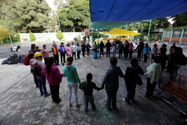 Las personas que viven en un refugio porque sus hogares sufrieron daños en un terremoto, se unen en una oración después de un temblor que se sintió en la Ciudad de México, México, 23 de septiembre de 2017. REUTERS / Daniel Becerril