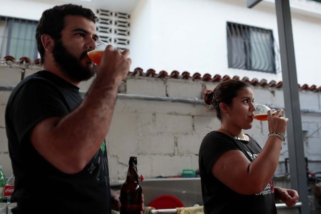 Victor Querales (L), one of the owners of Social Club brewery, and a worker drink craft beer in a beer garden at the garage of his brewery in Caracas, Venezuela September 15, 2017. Picture taken September 15, 2017. REUTERS/Marco Bello