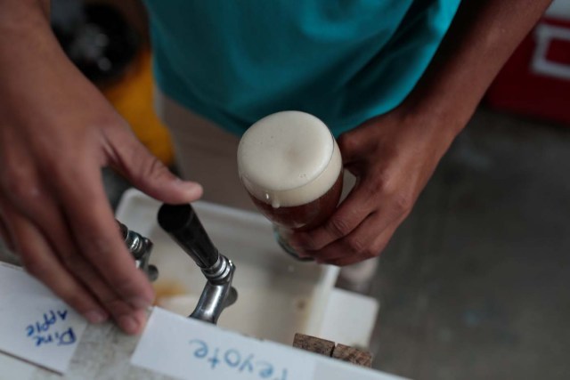 A worker drafts a glass of craft beer from a pump in a beer garden at the garage of Social Club brewery in Caracas, Venezuela, September 15, 2017. Picture taken September 15, 2017. REUTERS/Marco Bello