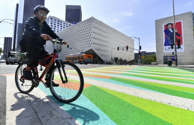 A cyclist rides across a painted sidewalk by Venezuelan-born artist Carlos Cruz-Diez across from the Broad Museum in Los Angeles, California on September 14, 2017, where the painted crosswalks are a part of the Pacific Standard Time LA/LA Show, an exploration of Latino and Latin American Art in dialogue with Los Angeles. / AFP PHOTO / FREDERIC J. BROWN