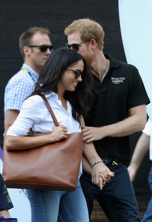 TORONTO, ON - SEPTEMBER 25: Prince Harry (R) and Meghan Markle (L) hold hands a Wheelchair Tennis match during the Invictus Games 2017 at Nathan Philips Square on September 25, 2017 in Toronto, Canada   Chris Jackson/Getty Images for the Invictus Games Foundation /AFP