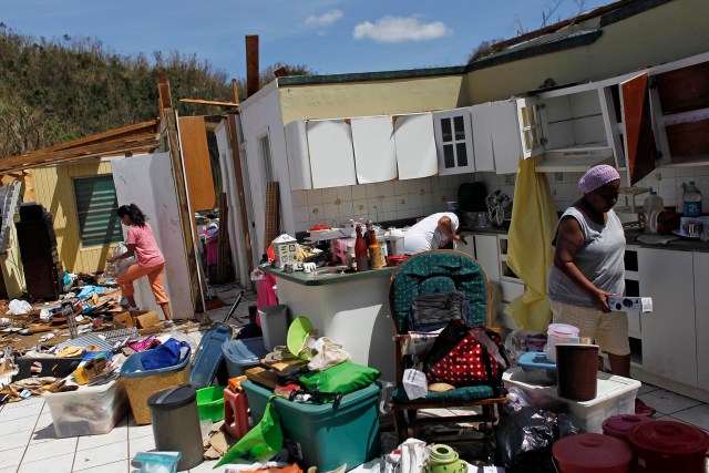 Family members collect belongings after hurricane force winds destroyed their house in Toa Baja, west of San Juan, Puerto Rico, on September 24, 2017 following the passage of Hurricane Maria. Authorities in Puerto Rico rushed on September 23, 2017 to evacuate people living downriver from a dam said to be in danger of collapsing because of flooding from Hurricane Maria. / AFP PHOTO / Ricardo ARDUENGO