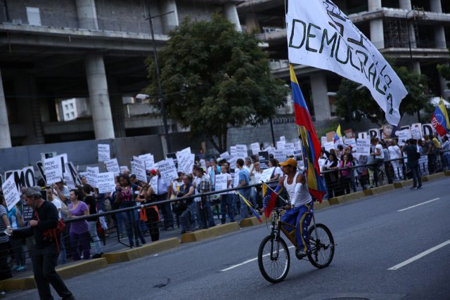 Un hombre en una bicicleta va junto a la gente que marcha rindiendo homenaje a las víctimas de la violencia en las protestas contra el gobierno de Nicolás Maduro, en Caracas, el 30 de agosto de 2017. REUTERS/Andres Martinez Casares -