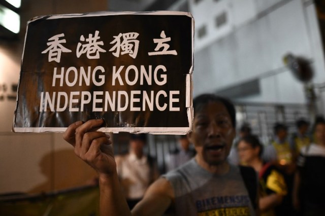 An activist holds a placard that reads "Hong Kong Independence" outside the Chinese Liaison office after an annual protest march on China's National Day in Hong Kong on October 1, 2017. / AFP PHOTO / Anthony WALLACE