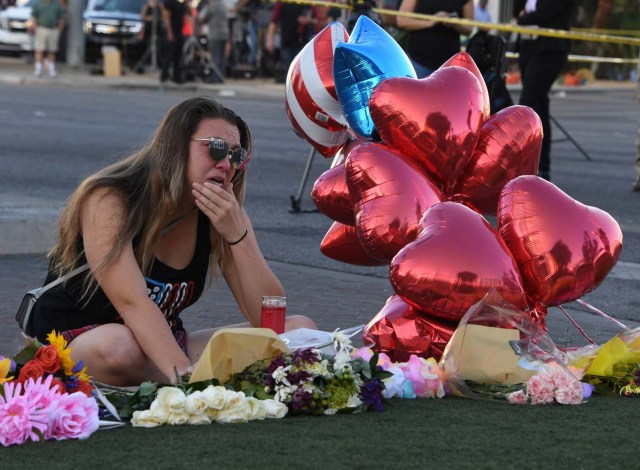 Destiny Alvers who attended the Route 91 country music festival and helped rescue her friend who was shot, reacts at a makeshift memorial on the Las Vegas Strip in Las Vegas, Nevada on October 3, 2017, after a gunman killed 59 people and wounded more than 500 others when he opened fire from a hotel window on a country music festival. Police said the gunman, a 64-year-old local resident named as Stephen Paddock, had been killed after a SWAT team responded to reports of multiple gunfire from the 32nd floor of the Mandalay Bay, a hotel-casino next to the concert venue. / AFP PHOTO / Mark RALSTON