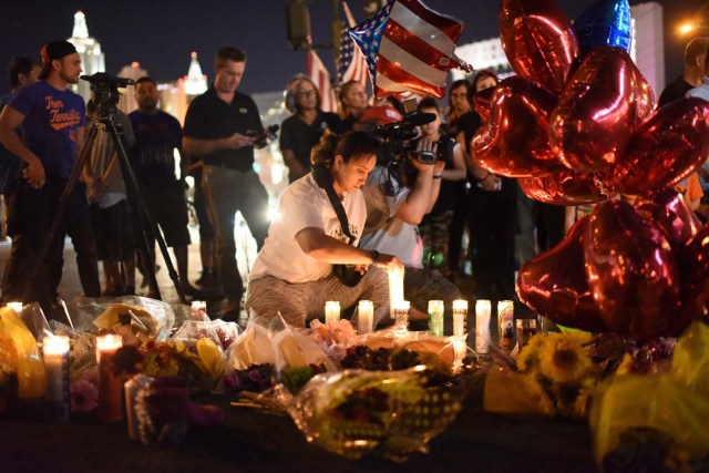 A woman lights a candle at a makeshift memorial near the Mandalay Hotel on the Las Vegas Strip, in Las Vegas, Nevada on October 3, 2017, after a gunman killed 58 people and wounded more than 500 others, before taking his own life, when he opened fire from a hotel on a country music festival. Police said the gunman, a 64-year-old local resident named as Stephen Paddock, had been killed after a SWAT team responded to reports of multiple gunfire from the 32nd floor of the Mandalay Bay, a hotel-casino next to the concert venue. / AFP PHOTO / Robyn Beck