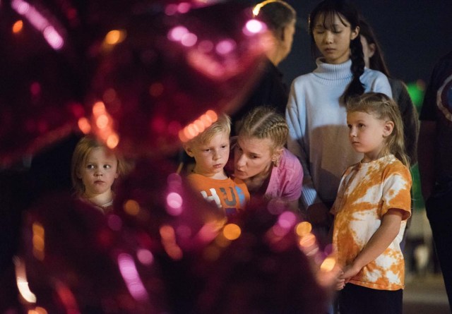 A woman talks with her children at a makeshift memorial near the Mandalay Hotel on the Las Vegas Strip, in Las Vegas, Nevada on October 3, 2017, after a gunman killed 58 people and wounded more than 500 others, before taking his own life, when he opened fire from a hotel on a country music festival. Police said the gunman, a 64-year-old local resident named as Stephen Paddock, had been killed after a SWAT team responded to reports of multiple gunfire from the 32nd floor of the Mandalay Bay, a hotel-casino next to the concert venue. / AFP PHOTO / Robyn Beck