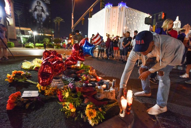 A man places a candle at a makeshift memorial near the Mandalay Hotel on the Las Vegas Strip, in Las Vegas, Nevada on October 3, 2017, after a gunman killed 58 people and wounded more than 500 others, before taking his own life, when he opened fire from a hotel on a country music festival. Police said the gunman, a 64-year-old local resident named as Stephen Paddock, had been killed after a SWAT team responded to reports of multiple gunfire from the 32nd floor of the Mandalay Bay, a hotel-casino next to the concert venue. / AFP PHOTO / Robyn Beck