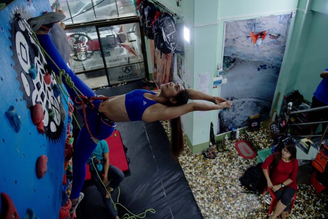 In this photograph taken on August 16, 2017, Khin Myat Thu Zar (C), a 32-year-old former lawyer who has been teaching yoga in Myanmar professionally for the last five years, performs a yoga pose on a climbing wall during a class at a studio in Yangon. First there was beer and paddleboard yoga. Then someone added goats to the mix. Now fitness buffs in Myanmar are taking the latest body-bending trend to whole new heights -- pulling off yoga poses on a climbing wall. / AFP PHOTO / Roberto SCHMIDT / TO GO WITH AFP STORY MYANMAR-LIFESTYLE-SPORT-YOGA-CLIMBING,FEATURE BY ATHENS ZAW ZAW