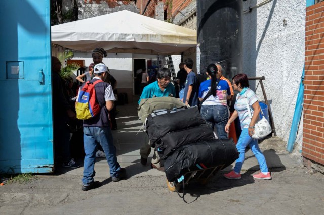 A man carries luggage of passengers at a bus terminal in Caracas on October 11, 2017 as scores of disappointed Venezuelans who see no end to the crisis choose to leave the country. Venezuela, which holds regional elections on October 15, is a country at the top of the Latin American continent that is in deep economic and political crisis. / AFP PHOTO / Federico PARRA