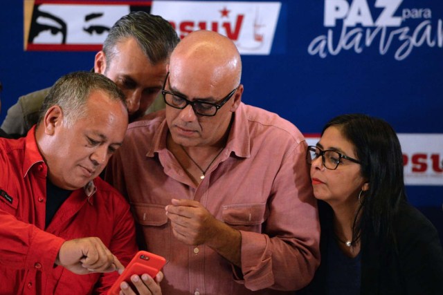 Jorge Rodriguez, mayor of Libertador municipality in Caracas and leader of the pro-government United Socialist Party of Venezuela (2-R), member of the Constituent Assembly Diosdado Cabello (L), Venezuelan Vice-President Tareck El Aissami (2-L) and president of the loyalist-packed Venezuelan Constituent Assembly, Delcy Rodriguez, look at Cabello's cellphone before delivering a press conference, as they wait for the results of the regional elections at the ruling party campaign headquarters in Caracas on October 15, 2017. Millions of Venezuelans voted peacefully in regional elections on Sunday following months of violent protests earlier this year aimed at unseating President Nicolas Maduro. No official turnout figures were available, but an electoral commission source estimated turnout at around 60 percent. / AFP PHOTO / FEDERICO PARRA