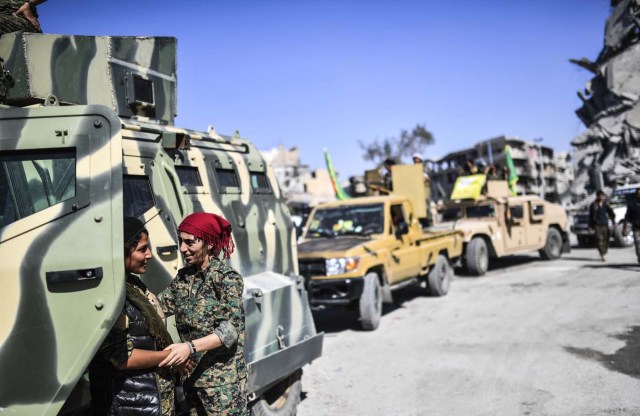 Kurdish female fighters of the Syrian Democratic Forces (SDF) gather during a celebration at the iconic Al-Naim square in Raqa on October 19, 2017, after retaking the city from Islamic State (IS) group fighters. The SDF fighters flushed jihadist holdouts from Raqa's main hospital and municipal stadium, wrapping up a more than four-month offensive against what used to be the inner sanctum of IS's self-proclaimed "caliphate". / AFP PHOTO / BULENT KILIC