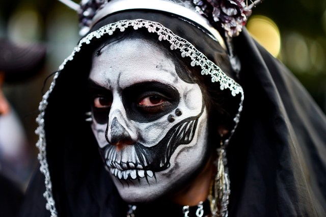 A woman disguised as "Catrina" (Mexican representation of death) takes part in the "Catrinas Parade" along Reforma Avenue, in Mexico City on October 22, 2017. Mexicans get ready to celebrate the Day of the Dead highlighting the character of La Catrina which was created by cartoonist Jose Guadalupe Posada, famous for his drawings of typical local, folkloric scenes, socio-political criticism and for his illustrations of "skeletons" or skulls, including La Catrina. / AFP PHOTO / RONALDO SCHEMIDT