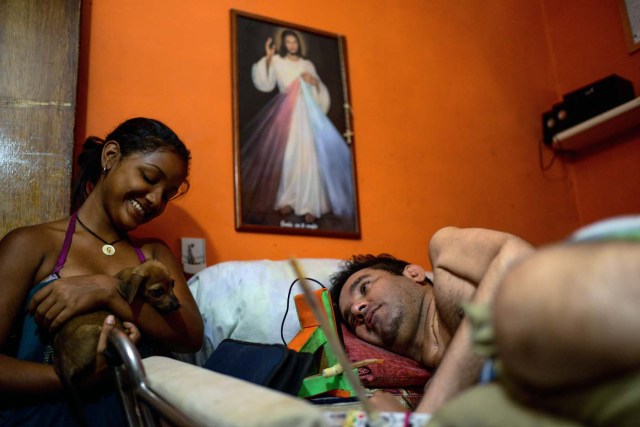 Marco Guillen (R), a 45-year-old quadriplegic, talks with his daughter Daikellys Mosquera at his house in Barquisimeto, Lara state, Venezuela on October 23, 2017. Marco Guillen became quadriplegic in an accident twelve years ago, amid Venezuela's deep economical crisis he desperately asks President Maduro's government to help him to live with dignity, meeting his medical necessities otherwise he pleads for euthanasia. / AFP PHOTO / FEDERICO PARRA / TO GO WITH AFP STORY by MARGIONI BERMUDEZ