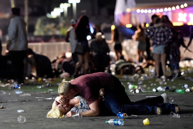 LAS VEGAS, NV - OCTOBER 01: A man lays on top of a woman as others flee the Route 91 Harvest country music festival grounds after a active shooter was reported on October 1, 2017 in Las Vegas, Nevada. A gunman has opened fire on a music festival in Las Vegas, leaving at least 2 people dead. Police have confirmed that one suspect has been shot. The investigation is ongoing. David Becker/Getty Images/AFP