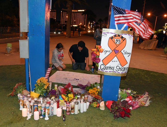 LAS VEGAS, NV - OCTOBER 03: People sign a poster at a makeshift memorial at the base of the Welcome to Fabulous Las Vegas sign in memory of the victims of Sunday night's shooting, on October 3, 2017 in Las Vegas, Nevada. Late Sunday night, a lone gunman killed at least 59 people and injured more than 500 after he opened fire on a large crowd at the Route 91 Harvest country music festival. The massacre is one of the deadliest mass shooting events in U.S. history.   Ethan Miller/Getty Images/AFP