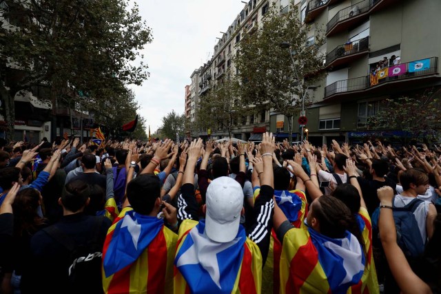 People raise hands and shout slogans outside People's Party (PP) regional headquarters in Barcelona, Spain, October 3, 2017. REUTERS/Juan Medina