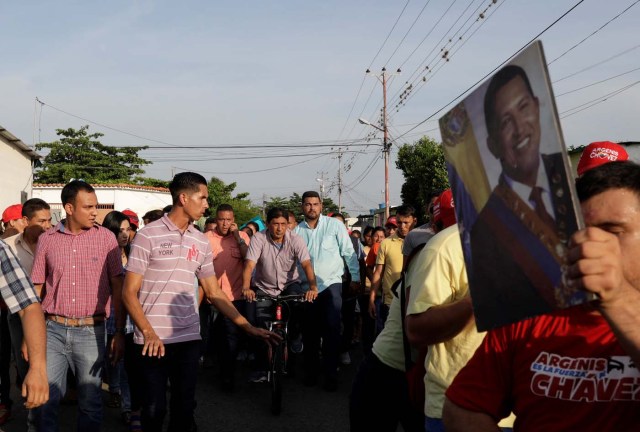 A supporter of the ruling Socialist Party's candidate for Barinas state Argenis Chavez (C), holds a picture of his brother, the late President of Venezuela Hugo Chavez, during a campaign event on the outskirts of Barinas, Venezuela, October 2, 2017. Picture taken on October 2, 2017. REUTERS/Ricardo Moraes