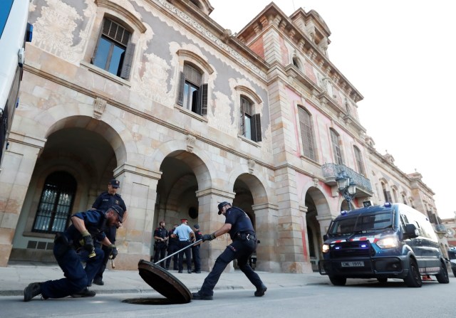 Oficiales de la policía regional de Catalunya, Mossos D'esquadra, buscan bajo una tapa de alcantarilla fuera de la asamblea regional de Barcelona, España, 10 de octubre de 2017. REUTERS / Gonzalo Fuentes