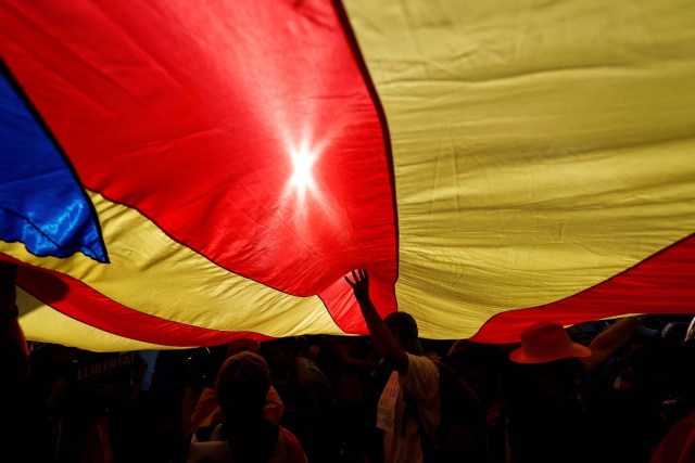 People stand under a giant separatist Catalonian flag during a demonstration organised by Catalan pro-independence movements ANC (Catalan National Assembly) and Omnium Cutural, following the imprisonment of their two leaders Jordi Sanchez and Jordi Cuixart, in Barcelona, Spain October 21, 2017. REUTERS/Rafael Marchante