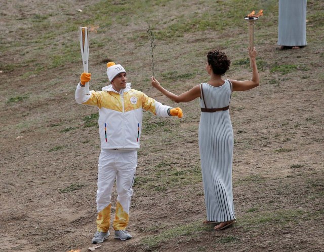Olympics - Lighting Ceremony of the Olympic Flame Pyeongchang 2018 - Ancient Olympia, Olympia, Greece - October 24, 2017 Greek actress Katerina Lehou, playing the role of High Priestess passes the flame to Greek cross country skiing athlete Apostolos Aggelis during the Olympic flame lighting ceremony for the Pyeongchang 2018 Winter Olympics REUTERS/Costas Baltas