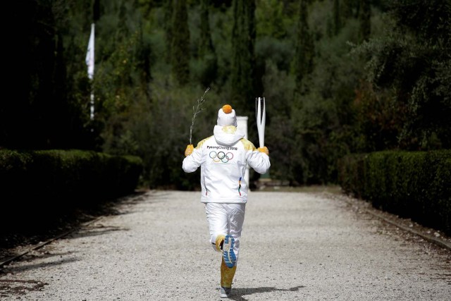 Olympics - Lighting Ceremony of the Olympic Flame Pyeongchang 2018 - Ancient Olympia, Olympia, Greece - October 24, 2017 First torchbearer Greek cross country skiing athlete Apostolos Aggelis runs with the Olympic flame and an olive branch at the Pierre de Coubertin monument during the Olympic flame lighting ceremony for the Pyeongchang 2018 Winter Olympics REUTERS/Alkis Konstantinidis