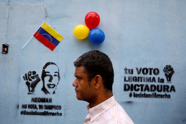 FILE PHOTO: A man walks in front of graffiti that reads "Neomar does not vote, neither do I" and "Your vote legitimizes the dictatorship", referring to Neomar Lander, who died during confrontations with security forces, during a nationwide election for new governors in Caracas, Venezuela, October 15, 2017. REUTERS/Carlos Garcia Rawlins/File Photo