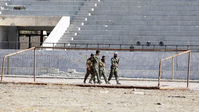 Soldados de las Fuerzas Democráticas Sirias (SDF) caminan por el estadio de Raqa (Siria), uno de los últimos lugares arrebatados al Estado Islámico en la ciudad. 18 de octubre de 2017.