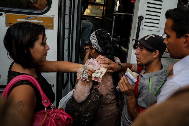 Fotografías del 10 de octubre del 2017, de un grupo de personas que pagan su pasaje para subir a un bus de transporte público en la ciudad de Caracas (Venezuela). Los altos costos de mantenimiento, la disminución de importación de repuestos, una galopante inflación y la escasez de efectivo tienen al sistema de transporte de Venezuela en jaque, mientras la población padece los efectos de esta crisis con un pasaje inestable y largos tiempos de espera para trasladarse. EFE/MIGUEL GUTIÉRREZ