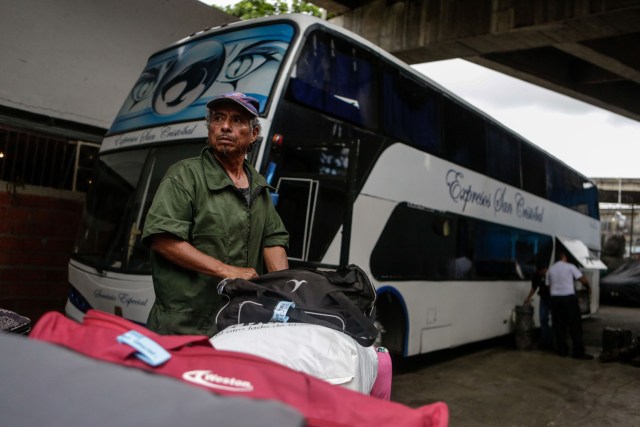 ACOMPAÑA CRÓNICA: VENEZUELA CRISIS - CAR02. CARACAS (VENEZUELA), 05/10/2018.- Fotografía del 29 de septiembre de 2017, que muestra a un empleado de la agencia de viajes "Cruz Del Sur" mientras carga las maletas de los viajeros en un autobús en Caracas (Venezuela) rumbo a diferentes destinos suramericanos. La reducción de oferta y el alto costo de boletos aéreos internacionales han obligado a muchos venezolanos a migrar por vía terrestre a diferentes países de Suramérica en búsqueda de alimentos, salud, seguridad y un "futuro", un viaje que puede tomar entre día y medio y once días, dependiendo qué tan al sur quieran llegar. EFE/Cristian Hernández