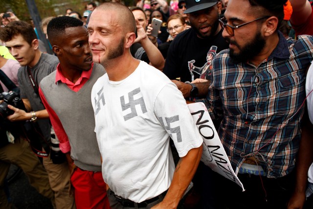 GAINESVILLE, FL - OCTOBER 19: A man wearing a shirt with swastikas is forced away from the scene by the crowd moments after being punched by an unidentified member of the crowd near the site of a planned speech by white nationalist Richard Spencer, who popularized the term 'alt-right', at the University of Florida campus on October 19, 2017 in Gainesville, Florida. A state of emergency was declared on Monday by Florida Gov. Rick Scott to allow for increased law enforcement due to fears of violence.   Brian Blanco/Getty Images/AFP