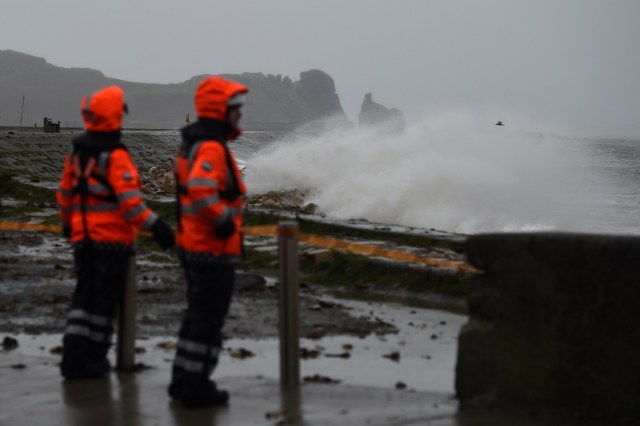 Members of the Irish Coast Guard stand on Howth Pier to prevent people walking along the pier as Storm Brian creates large waves, in Dublin, Ireland October 21, 2017. REUTERS/Clodagh Kilcoyne