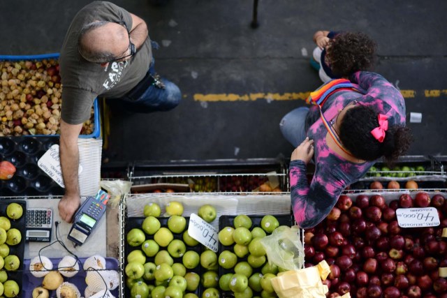 A fruits and vegetables seller waits for customers at the municipal market of Chacao in Caracas on November 2, 2017. This week, Venezuelan President Nicolas Maduro introduced a new bank note of 100,000 Bolivars - five times the current largest denomination - and announced a 30 percent minimum wage hike. / AFP PHOTO / FEDERICO PARRA