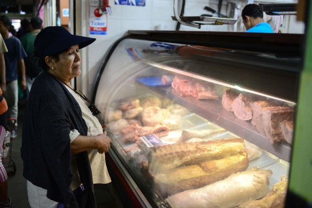 A woman buys meat at the municipal market of Chacao in Caracas on November 2, 2017. This week, Venezuelan President Nicolas Maduro introduced a new bank note of 100,000 Bolivars - five times the current largest denomination - and announced a 30 percent minimum wage hike. / AFP PHOTO / FEDERICO PARRA