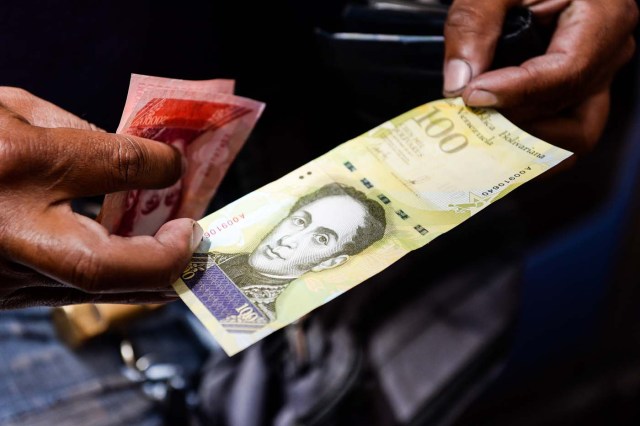 A man shows a new one hundred thousand-Bolivar-note in Caracas on November 9, 2017. The new bill is worth 29,89 US dollars in the official market and 2 dollars in the black market at November 9, 2017 exchange rate. / AFP PHOTO / FEDERICO PARRA