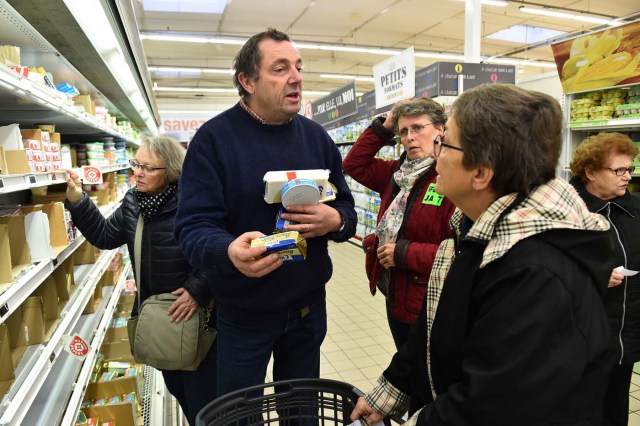 French farmer Ghislain De Viron (C) holds butter made from a blend of European Union milk as a substitute for French butter as he speaks to consummers in the hyper market Leclerc d'Alllonnes, near Le Mans, northwestern France, on November 10, 2017 during an action of French farmers to sell butter at a price that will remunerate them. / AFP PHOTO / JEAN-FRANCOIS MONIER