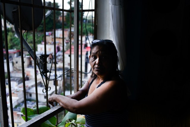 Luber Faneitte, a 56-year-old diagnosed with lung cancer, looks out the window of her house in the San Agustin shantytown in Caracas on November 10, 2017. In crisis-stricken Venezuela, the cost of the basic basket of goods soared to nearly 2.7 million bolivars in September, the equivalent of six minimum monthly wages. / AFP PHOTO / FEDERICO PARRA