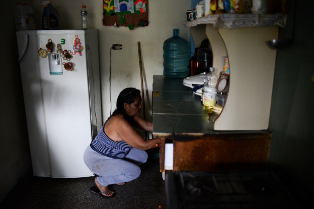 Luber Faneitte, a 56-year-old diagnosed with lung cancer, tidies the kitchen in her house in the San Agustin shantytown in Caracas on November 10, 2017. In crisis-stricken Venezuela, the cost of the basic basket of goods soared to nearly 2.7 million bolivars in September, the equivalent of six minimum monthly wages. / AFP PHOTO / FEDERICO PARRA