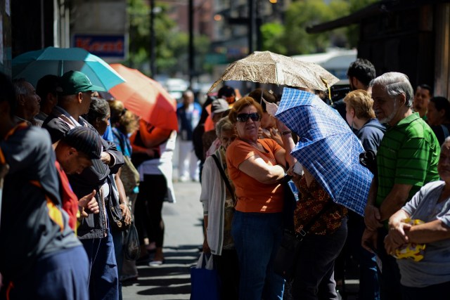 People queue outside a supermarket in Caracas to buy basic foodstuffs and household products on November 10, 2017. In crisis-stricken Venezuela, the cost of the basic basket of goods soared to nearly 2.7 million bolivars in September, the equivalent of six minimum monthly wages. / AFP PHOTO / FEDERICO PARRA