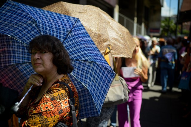 People queue outside a supermarket in Caracas to buy basic foodstuffs and household products on November 10, 2017. In crisis-stricken Venezuela, the cost of the basic basket of goods soared to nearly 2.7 million bolivars in September, the equivalent of six minimum monthly wages. / AFP PHOTO / FEDERICO PARRA